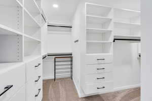 Spacious Primary bedroom walk in closet featuring light colored carpet