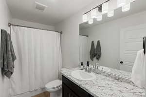 Bathroom featuring walk in shower, vanity, toilet, and hardwood / wood-style flooring