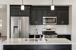 Kitchen featuring pendant lighting, an island with sink, and appliances with stainless steel finishes