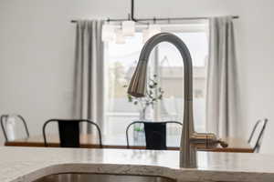 Room details featuring light stone countertops, a chandelier, and sink