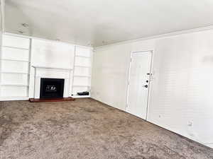 Unfurnished living room with carpet floors and crown molding