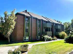 View of front of home featuring a balcony and a front lawn