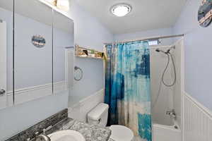 Full bathroom featuring a textured ceiling, shower / tub combo, vanity, and toilet