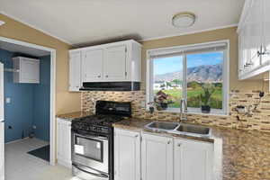 Kitchen with stainless steel gas range, white cabinetry, a mountain view, and sink