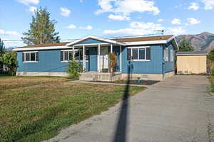 View of front of home featuring a front yard, a mountain view, and a shed