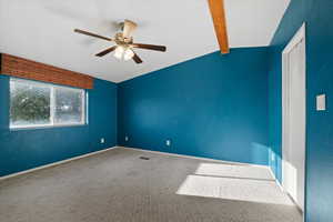 Carpeted spare room with vaulted ceiling with beams and ceiling fan