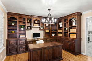 Office space featuring an inviting chandelier, light wood-type flooring, and ornamental molding