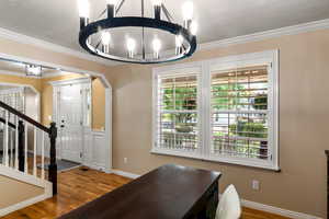 Interior space with ornamental molding, a notable chandelier, and hardwood / wood-style floors