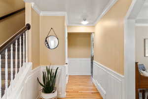 Hallway with light hardwood / wood-style floors and ornamental molding