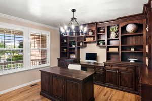 Office with light hardwood / wood-style flooring, a notable chandelier, and ornamental molding