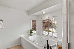 Bathroom with tile patterned flooring and tiled bath