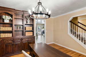 Dining space featuring an inviting chandelier, light hardwood / wood-style flooring, ornamental molding, and french doors