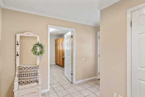 Hallway featuring light tile patterned floors and crown molding