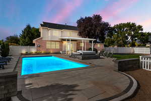 Pool at dusk featuring an outdoor living space and a patio area