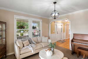 Living room featuring crown molding, hardwood / wood-style floors, and an inviting chandelier