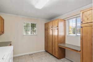 Kitchen with light tile patterned floors, plenty of natural light, washer and dryer, and crown molding