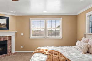 Bedroom featuring a fireplace, ornamental molding, and carpet