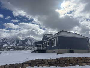 View of snow covered exterior with cooling unit and a mountain view