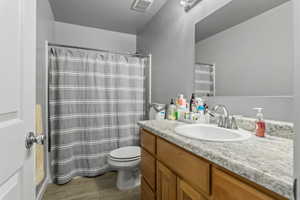 Bathroom with walk in shower, vanity, toilet, and hardwood / wood-style flooring