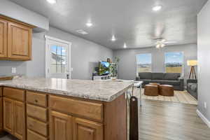 Kitchen featuring a textured ceiling, kitchen peninsula, ceiling fan, and light hardwood / wood-style flooring