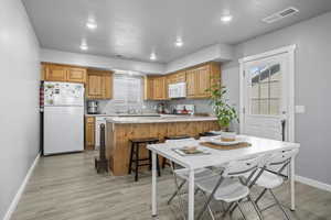 Kitchen featuring a kitchen breakfast bar, a wealth of natural light, white appliances, and light hardwood / wood-style floors