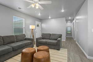 Living room with a textured ceiling, light hardwood / wood-style floors, and ceiling fan