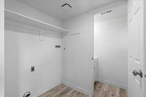 Laundry area with light wood-type flooring and hookup for an electric dryer