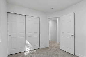 Unfurnished bedroom featuring light carpet and a closet