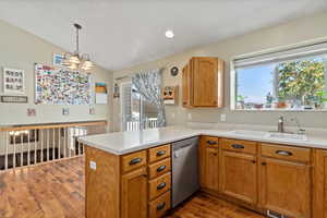 Kitchen featuring dishwasher, kitchen peninsula, vaulted ceiling, and a healthy amount of sunlight