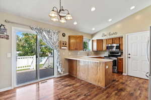 Kitchen featuring stainless steel appliances, kitchen peninsula, a healthy amount of sunlight, and dark hardwood / wood-style flooring