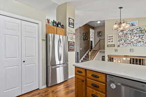 Kitchen with a chandelier, lofted ceiling, hanging light fixtures, stainless steel appliances, and dark hardwood / wood-style flooring