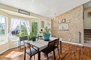 Dining area featuring wood-type flooring, a notable chandelier, and a wealth of natural light