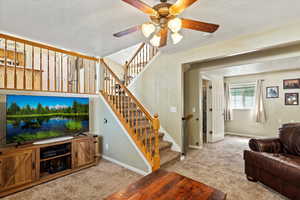 Living room featuring light carpet, ceiling fan, and a textured ceiling