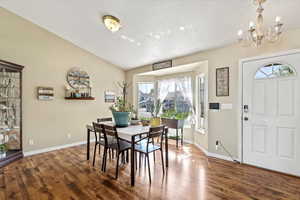 Dining area featuring lofted ceiling, a textured ceiling, a chandelier, and dark hardwood / wood-style floors