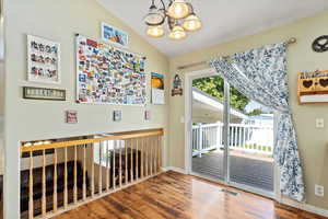 Interior space featuring an inviting chandelier, vaulted ceiling, and hardwood / wood-style floors