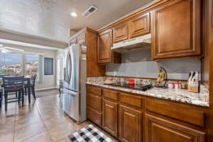 Kitchen with ceiling fan, light tile patterned flooring, stainless steel fridge, a textured ceiling, and black electric cooktop