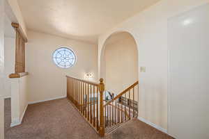 Hall featuring a textured ceiling and carpet flooring