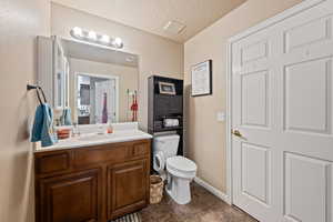 Bathroom featuring tile patterned floors, a textured ceiling, vanity, and toilet