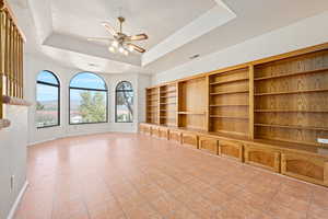 Unfurnished living room featuring ceiling fan, a raised ceiling, light tile patterned flooring, and a textured ceiling