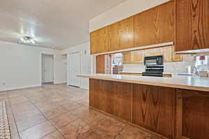 Kitchen with a textured ceiling, sink, kitchen peninsula, and black appliances