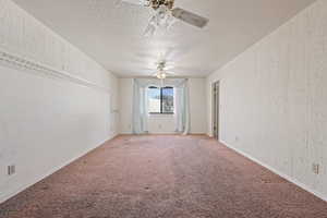 Unfurnished room featuring ceiling fan, carpet floors, and a textured ceiling