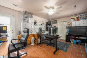 Tiled office with ceiling fan and a textured ceiling