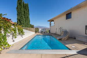 View of swimming pool with a water slide, a mountain view, and a patio area