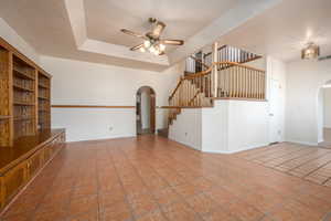 Unfurnished living room featuring a textured ceiling, tile patterned flooring, and ceiling fan