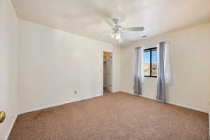 Carpeted empty room with a textured ceiling and ceiling fan