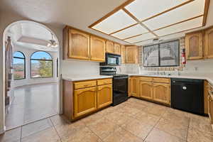 Kitchen featuring ceiling fan, light tile patterned flooring, sink, a textured ceiling, and black appliances