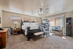 Bedroom with ceiling fan, a textured ceiling, and carpet flooring