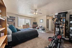 Carpeted bedroom with ceiling fan and a textured ceiling