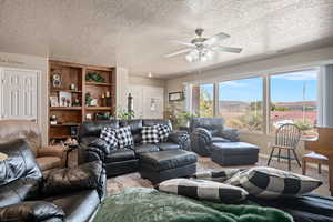 Carpeted living room featuring a textured ceiling and ceiling fan