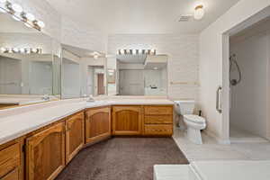 Bathroom with a tile shower, vanity, tile patterned flooring, and toilet